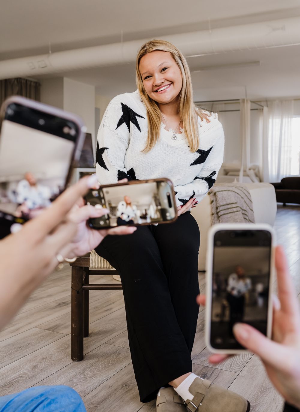 A series of photos showing someone taking pictures of a black cat sitting on a wooden floor with a smartphone camera.