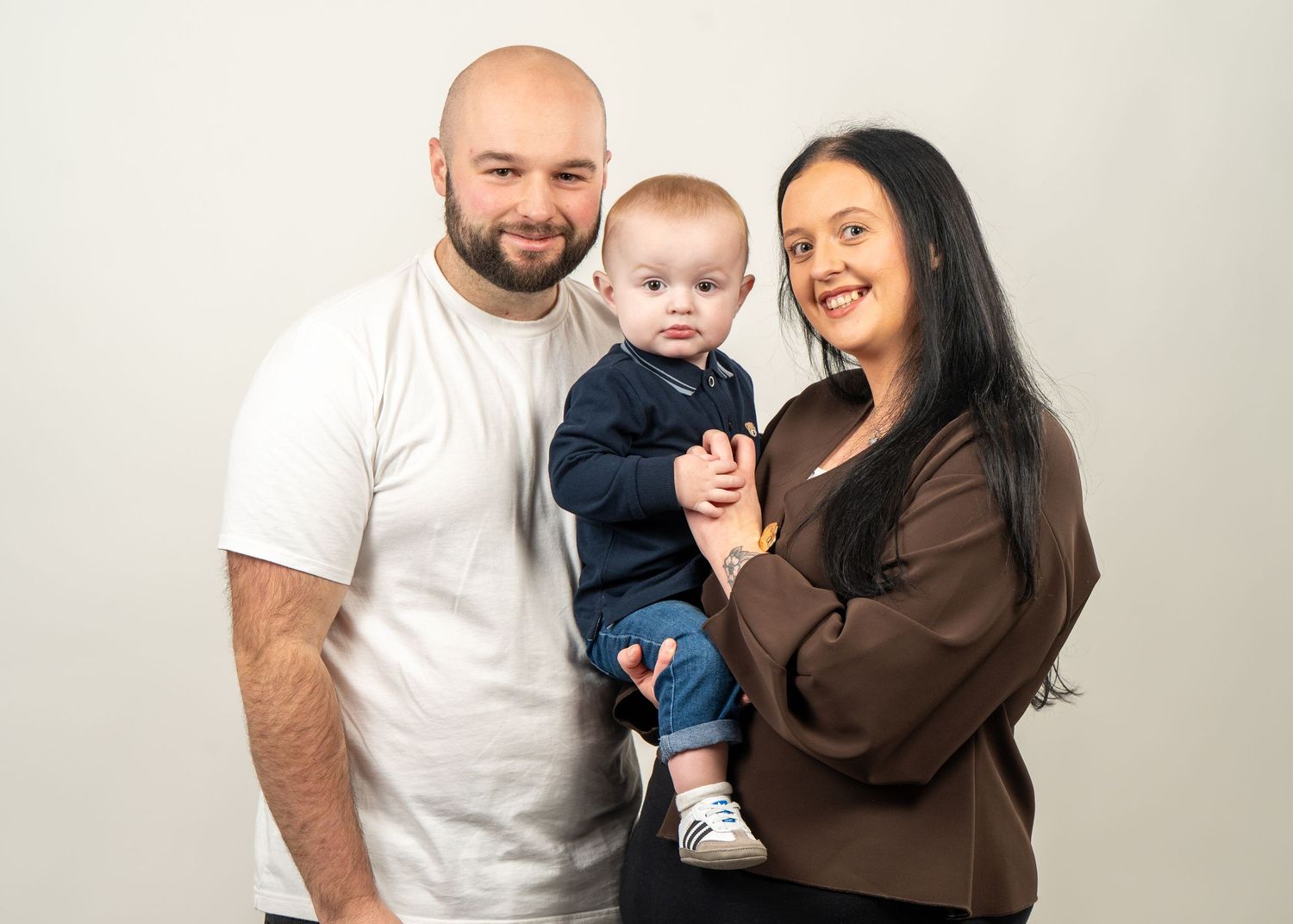 A family poses together against a light backdrop for a portrait studio photo.