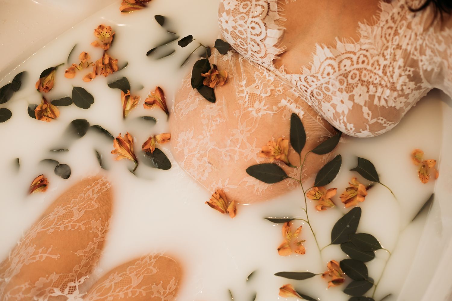 Cullman Alabama Photographer -Flowers and green leaves arranged on white fabric with delicate lace details in maternity shoot