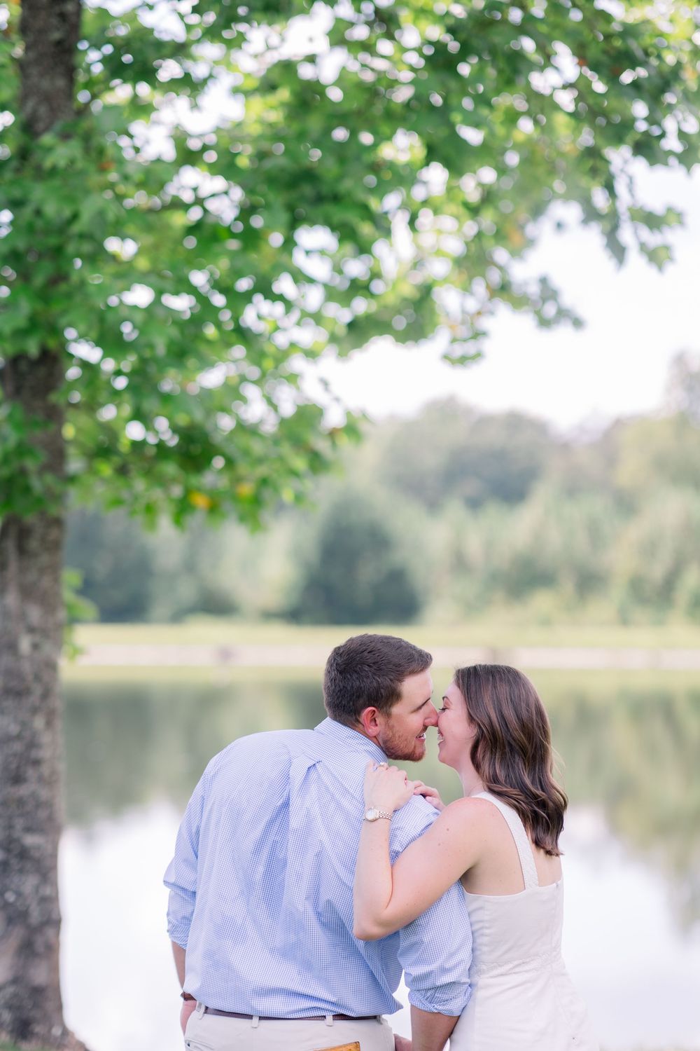 A romantic lakeside moment between a couple in coordinating blue and white outfits.