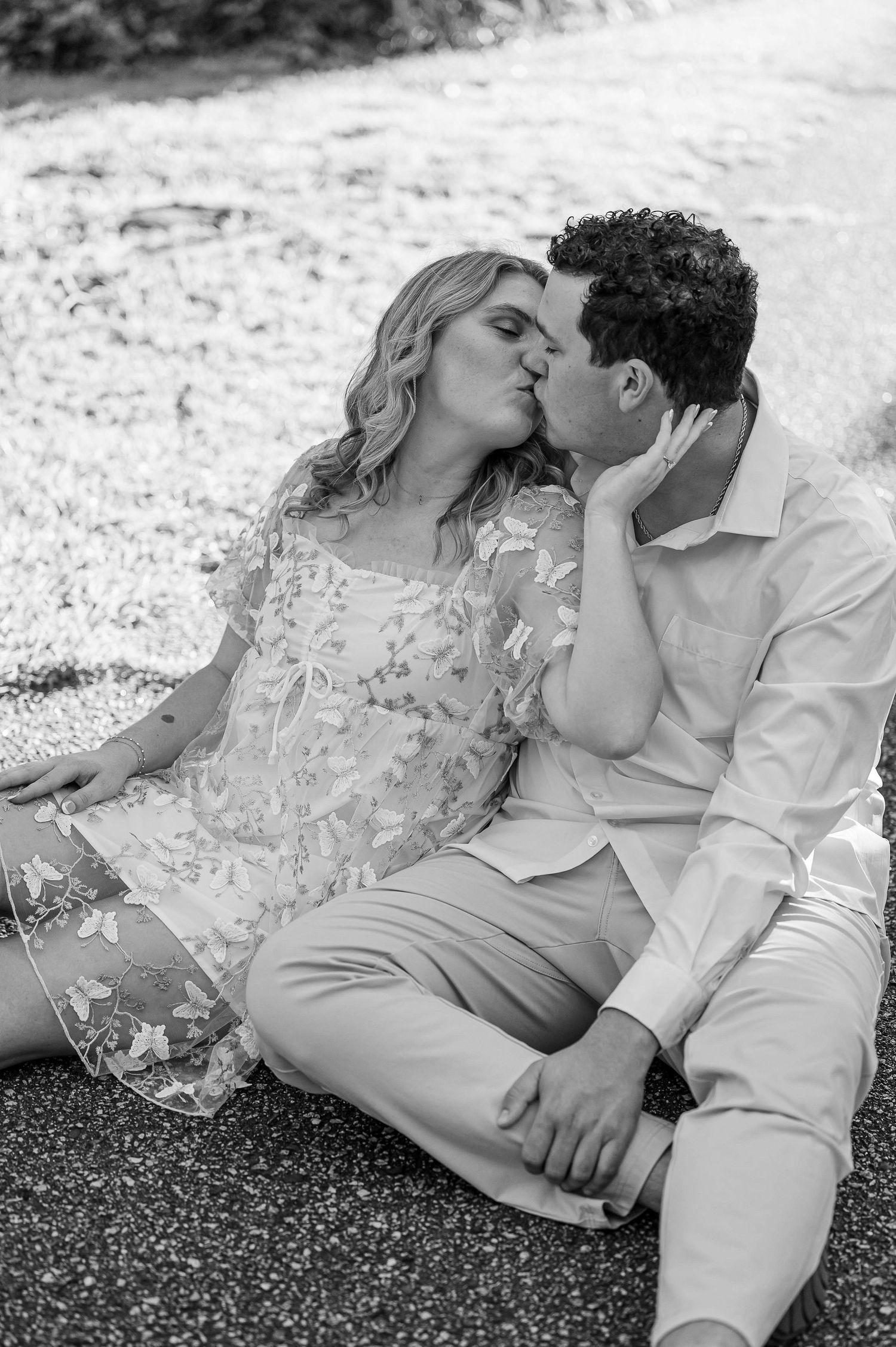 A black and white portrait of a couple sharing an intimate moment outdoors.