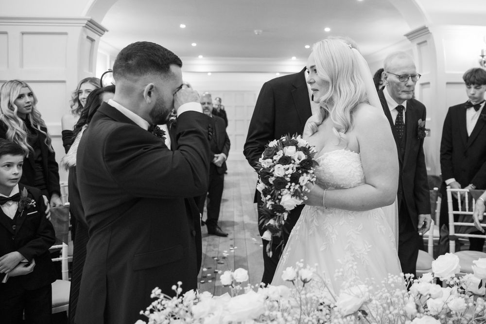 Elegant wedding ceremony scene with white floral arrangements and formal decor.