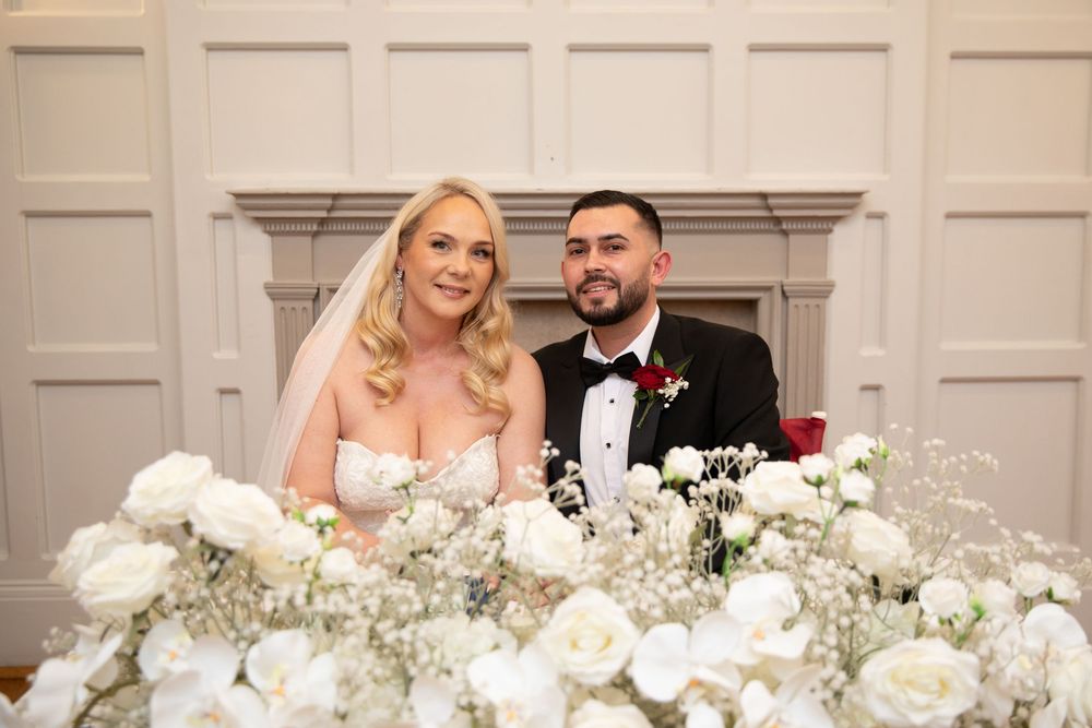 Elegant white wedding reception decor with floral arrangements and candlelight in a classic ballroom setting.