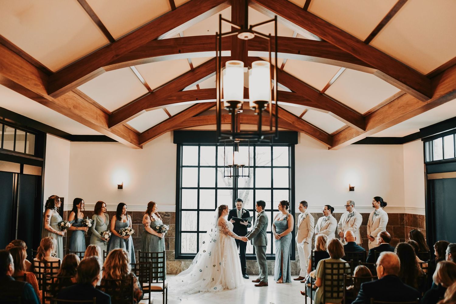 Modern winter wedding ceremony at The Dalmore Event Venue in Fort Worth with high arch ceilings and black rimmed window