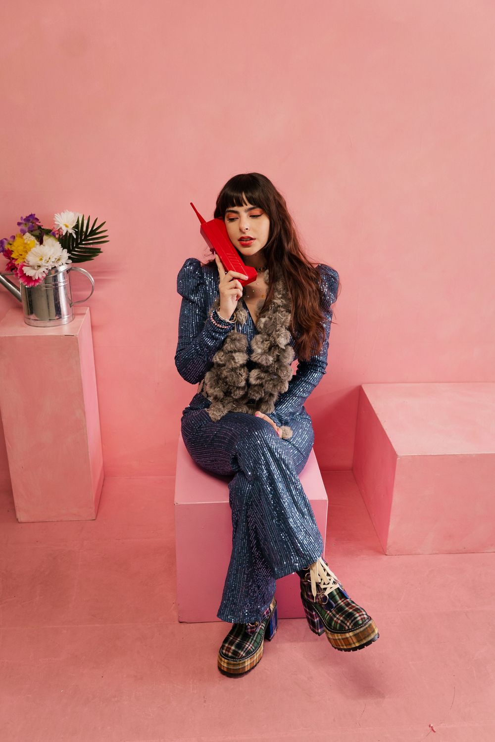 Person in blue lace dress and leopard print shoes poses against pink backdrop with various props and accessories.