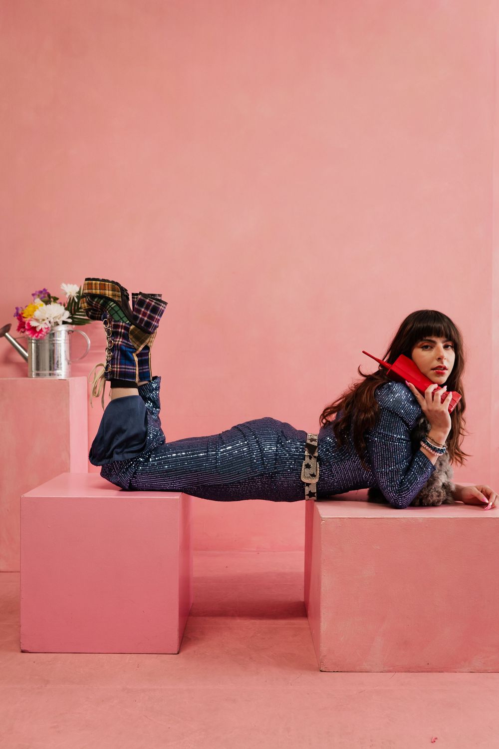 Person in denim outfit lying on pink geometric platforms in creative fashion photo series.
