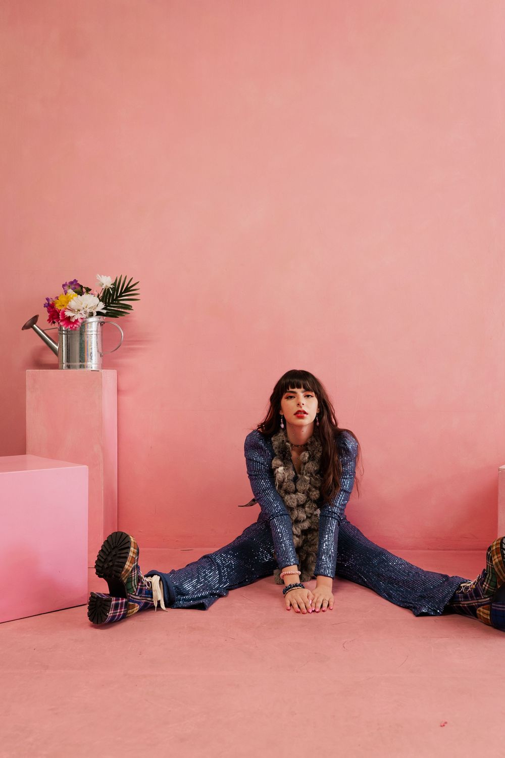 Person in denim outfit lying on pink floor in creative split photo series showing different poses.