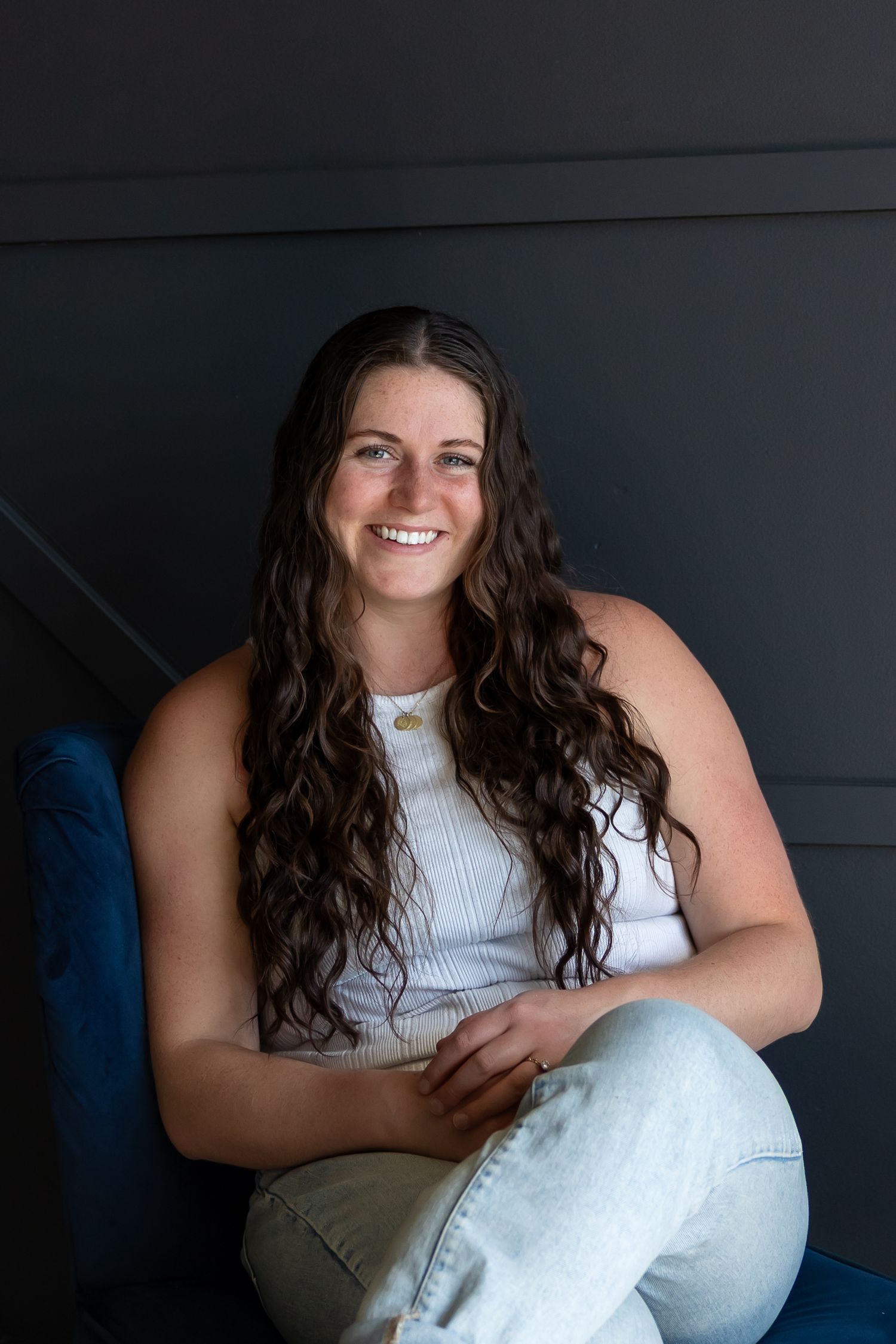 A series of portraits showing someone with long dark wavy hair sitting on a blue couch in a white sleeveless top.