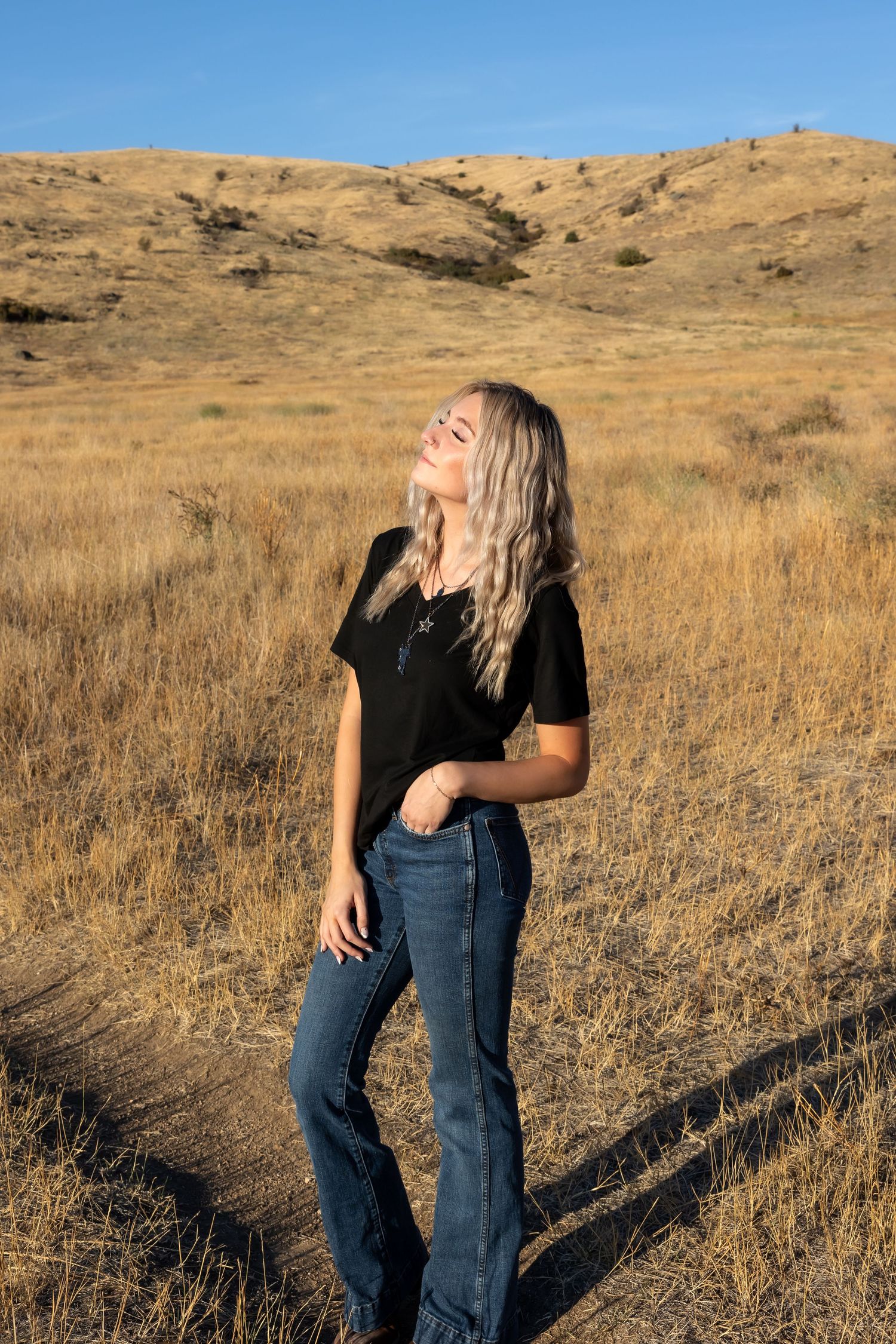 A casual photoshoot in a field with rolling hills and dry grass in the background.