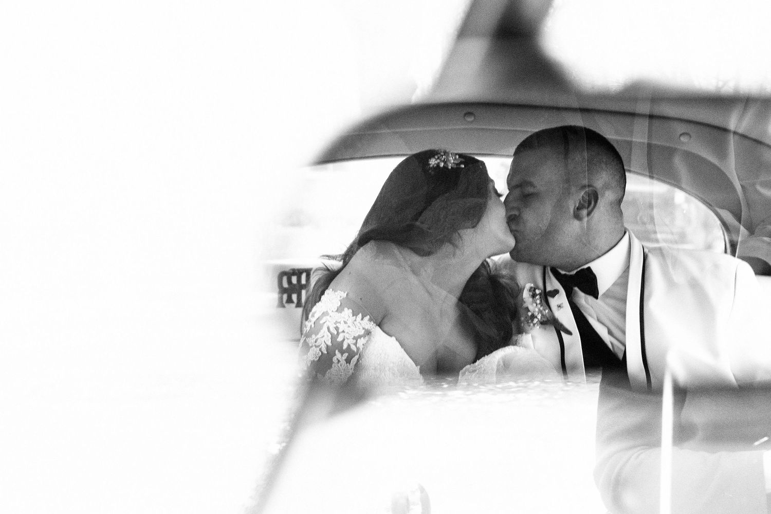 A romantic black and white wedding photo of a couple sharing an intimate moment under an umbrella.