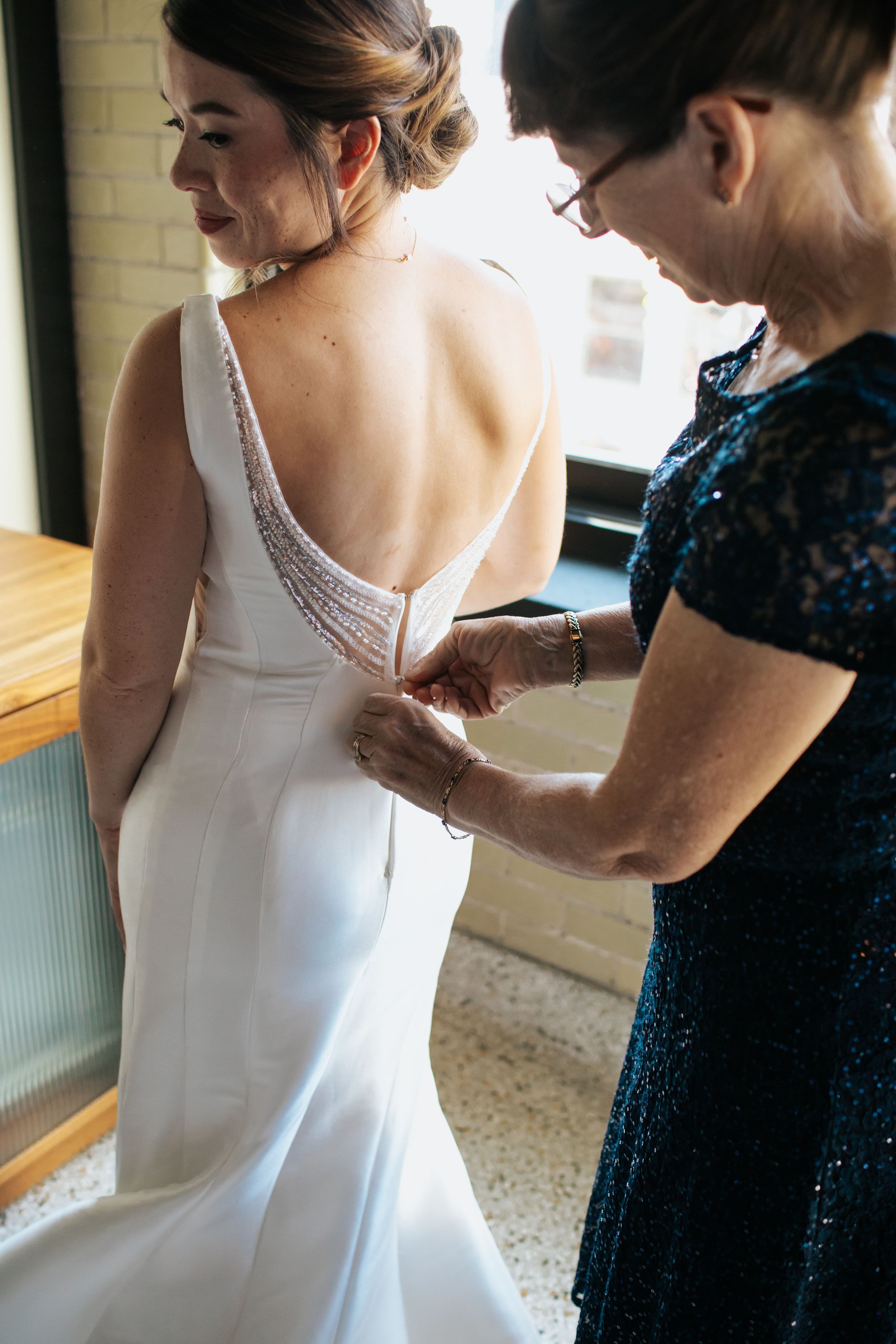Close-up sequence showing someone helping adjust the back of an elegant white wedding dress.