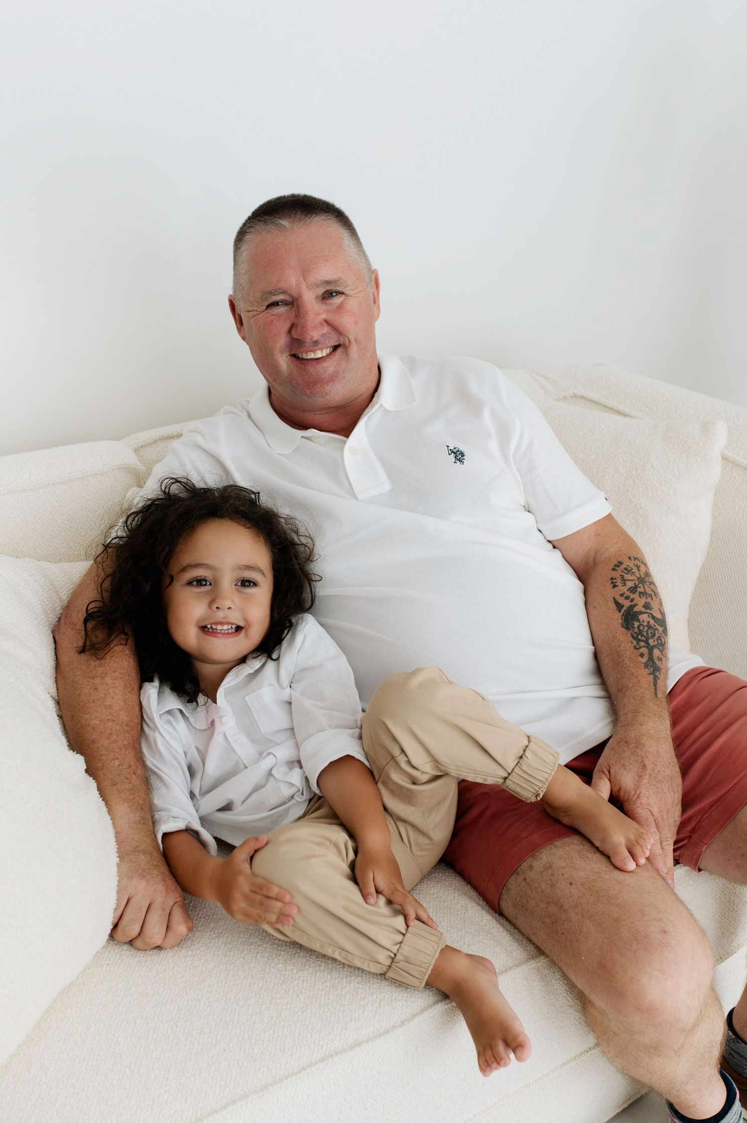 Four connected photos showing a tender moment between a parent and child relaxing together on a white couch.