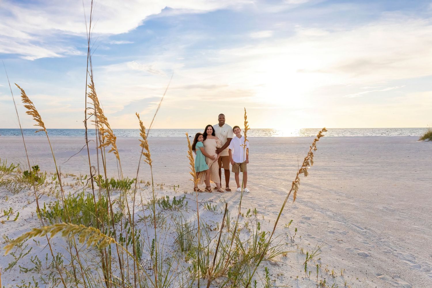 Couple silhouetted against sunset sky on peaceful beach with sea oats.