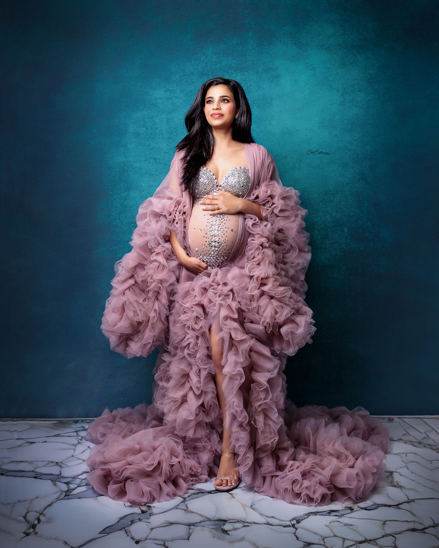 Ethereal dusty rose flowing fabric surrounds a pregnant woman during a fine art studio session.