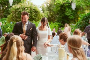 Wedding celebration at an outdoor garden reception with guests seated at decorated tables.