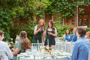 Elegant outdoor wedding reception with white tables and chairs surrounded by greenery.