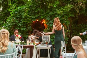 Outdoor wedding reception setup with white chairs and lush greenery backdrop.