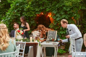 Wedding reception buffet setup with white chairs and tables in a lush garden setting.