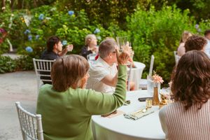 Wedding guests enjoying drinks and conversation at outdoor garden reception.