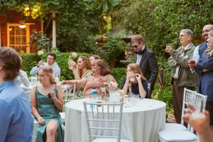 Guests seated at round tables enjoying an evening garden wedding reception.