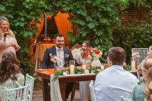Wedding reception dinner at an intimate outdoor venue with ivy-covered walls.
