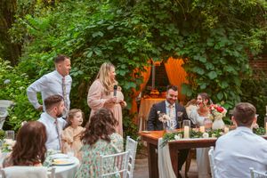 Wedding guests enjoying conversation at an outdoor garden reception with white chairs and natural decor.