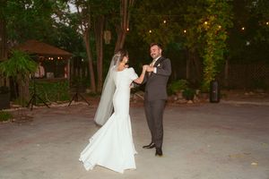 Wedding reception in a lush garden setting with white chairs and romantic lighting at dusk.