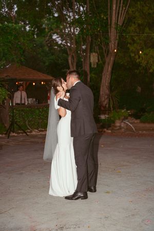 A couple shares their first dance on a patio during their evening wedding reception.