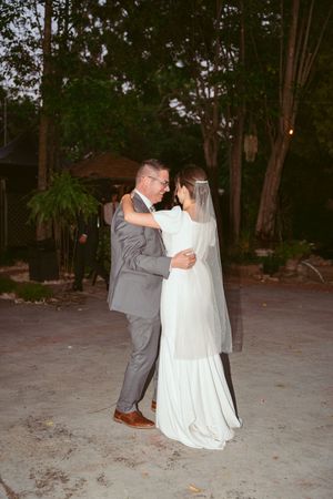 A couple sharing their first dance at a romantic outdoor evening wedding.