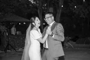 A couple laughing together during their wedding dance at dusk.
