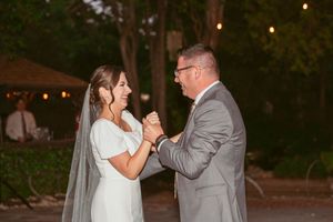 Couple sharing a romantic dance moment at twilight under string lights.