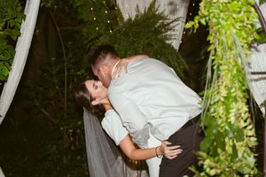 A romantic moment between newlyweds during their wedding reception in a garden setting.