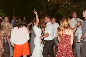 Wedding guests dance and celebrate at a lively indoor reception with colorful summer dresses and suits.