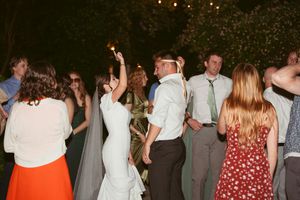 People dancing and celebrating at a nighttime wedding reception with guests in formal attire under outdoor lighting.