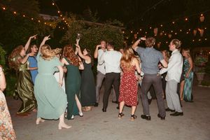Wedding guests dancing together under outdoor string lights at an evening reception celebration.