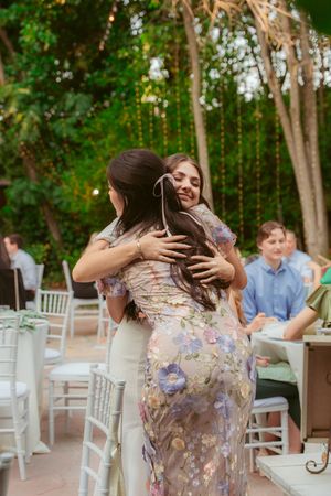 Wedding celebration in a green garden courtyard with white dining furniture and string lights.