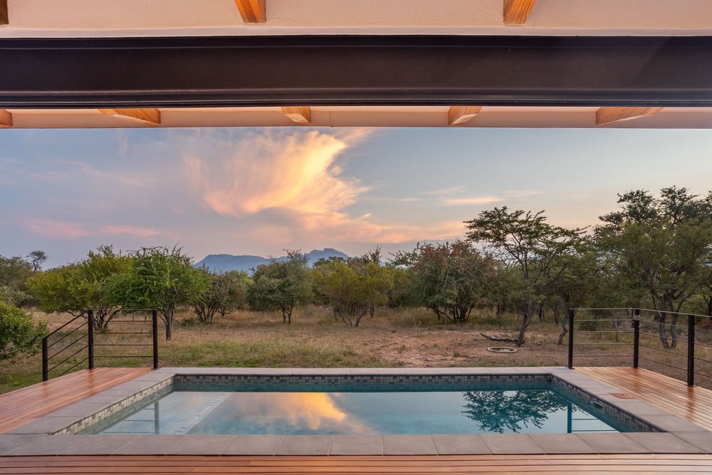 Luxury villa exterior at sunset with pool and patio area