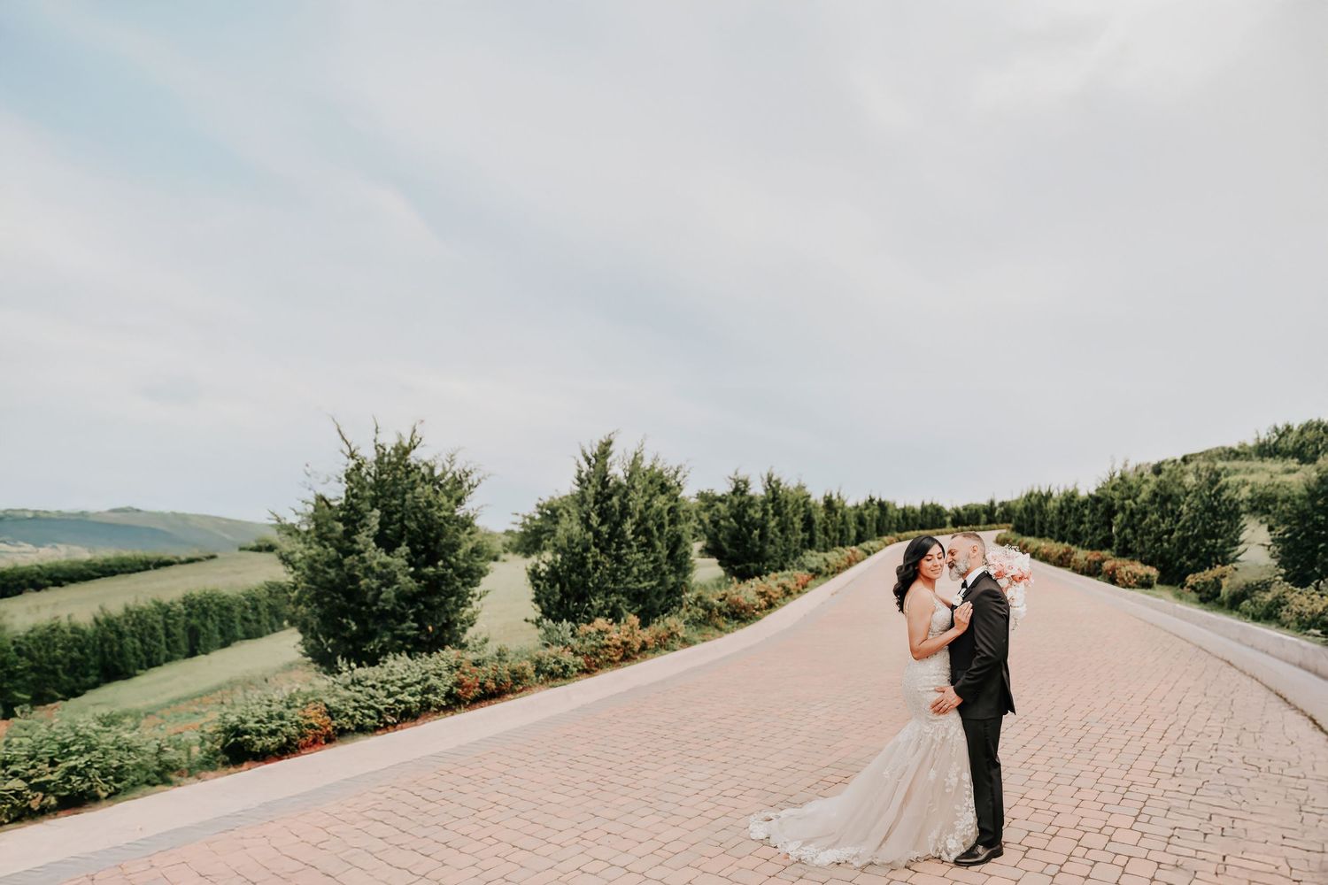 gorgeous wide angle photo of D'Vine Grace Vineyard of new bride and groom kissing after their wedding ceremony in the middle of the vineyard