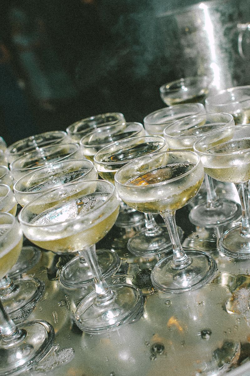 Multiple coupe glasses filled with sparkling champagne arranged on a silver tray for a celebration event.