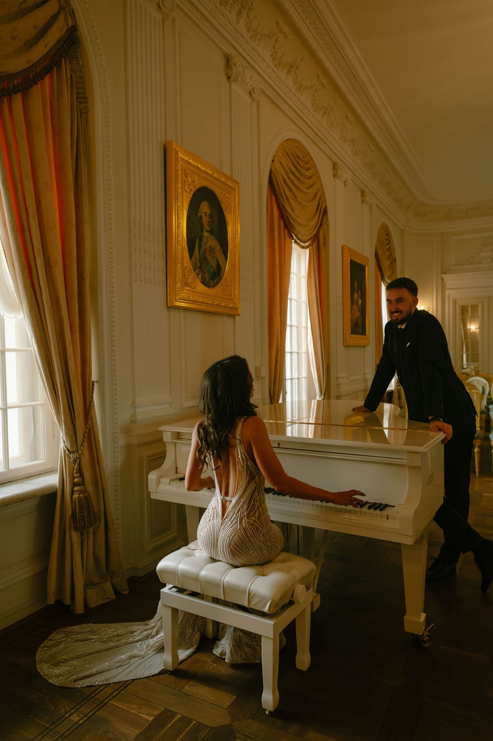 A romantic scene with a white piano in an elegant room with gold-framed portraits and draped windows.