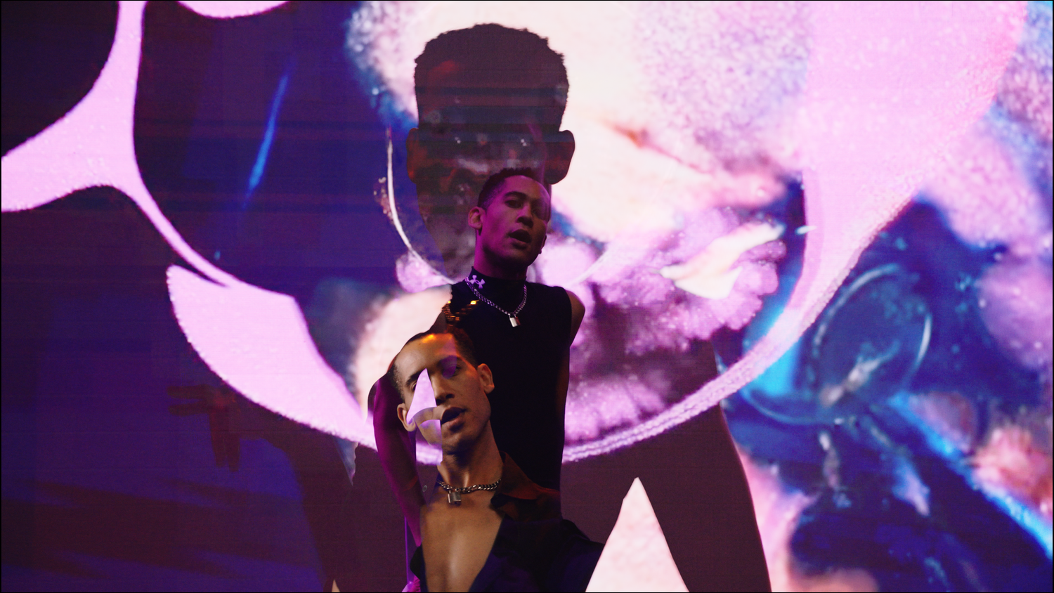 Person performs on stage with dramatic lighting and smoke effects against a purple and blue background.