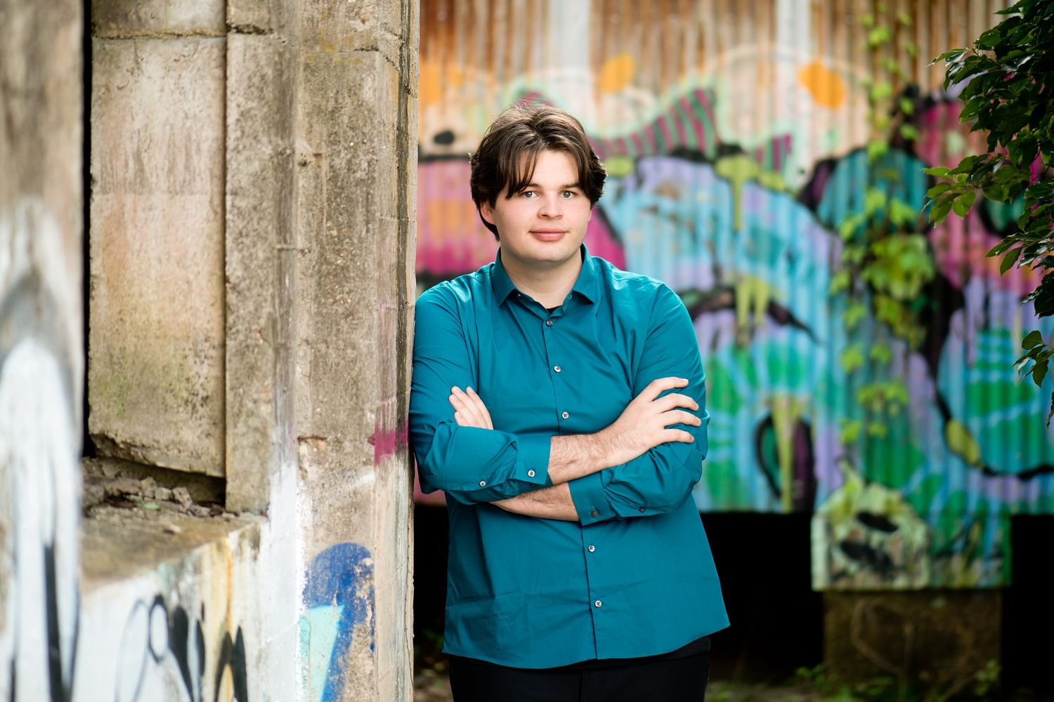 Portrait sequence against industrial backdrop with vibrant street art and concrete pillars.