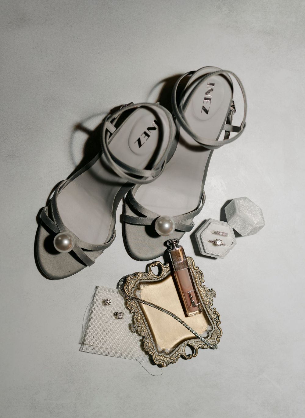 Wedding shoes and accessories arranged artistically on light gray background.