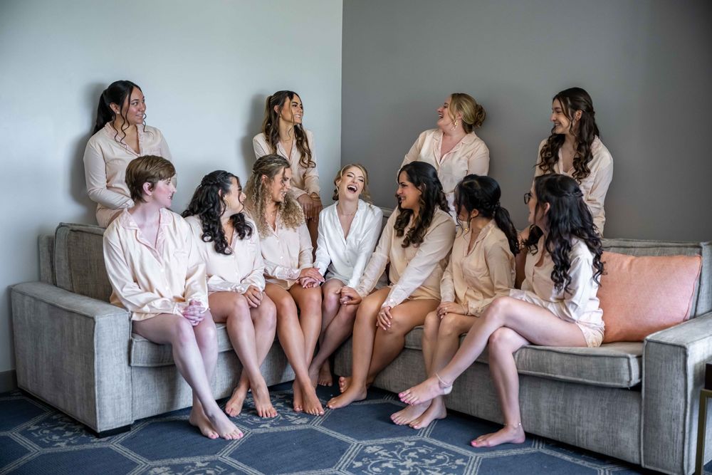 Group wearing matching silk robes sit together on a gray couch during a relaxing spa gathering.