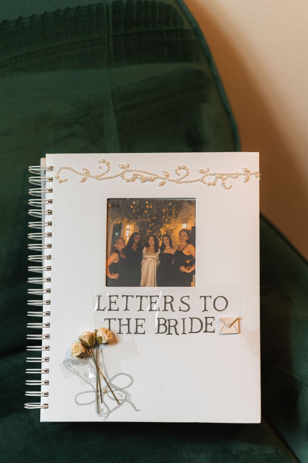 Letters to the Bride notebook with gold floral design and dried flowers on green background.