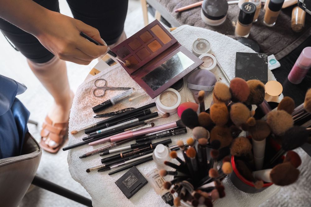 Assorted makeup brushes and beauty tools arranged on a white surface next to a container.