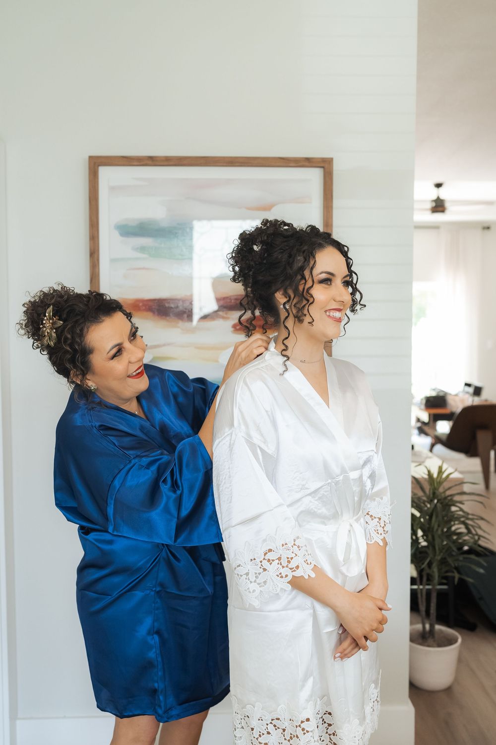 Two people in satin robes share a joyful moment while getting ready.