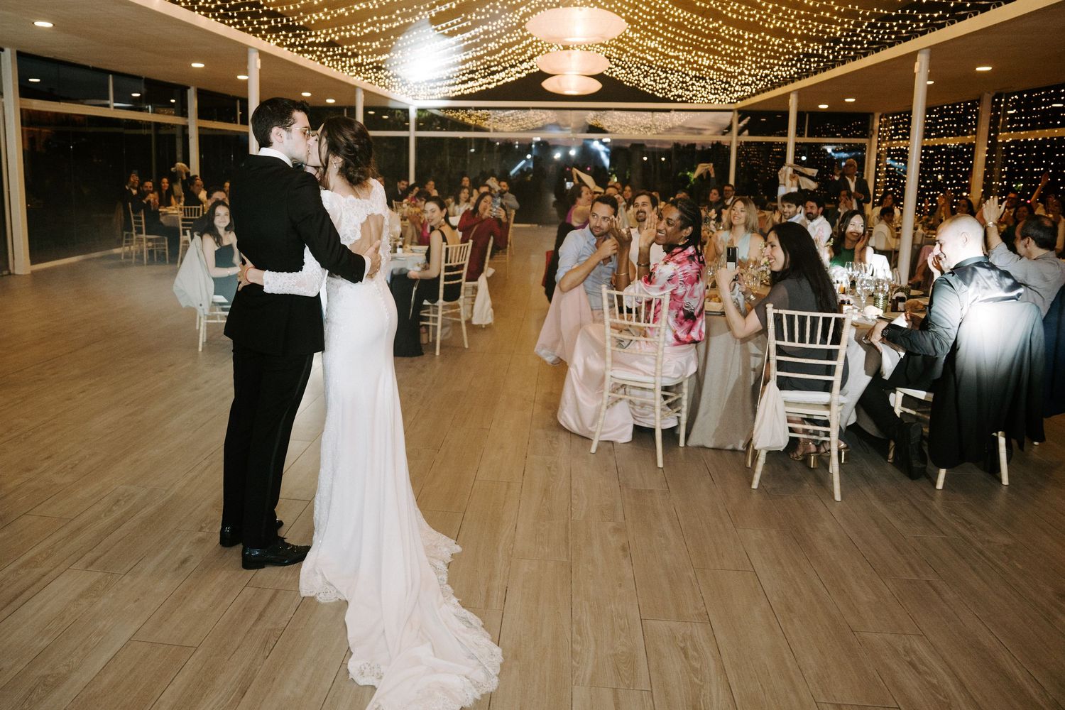 Wedding reception venue decorated with string lights and elegant table settings.