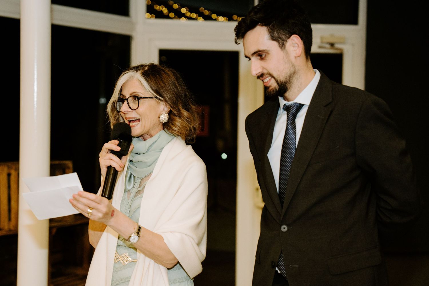 Wedding guests mingling and taking photos during an indoor reception celebration.
