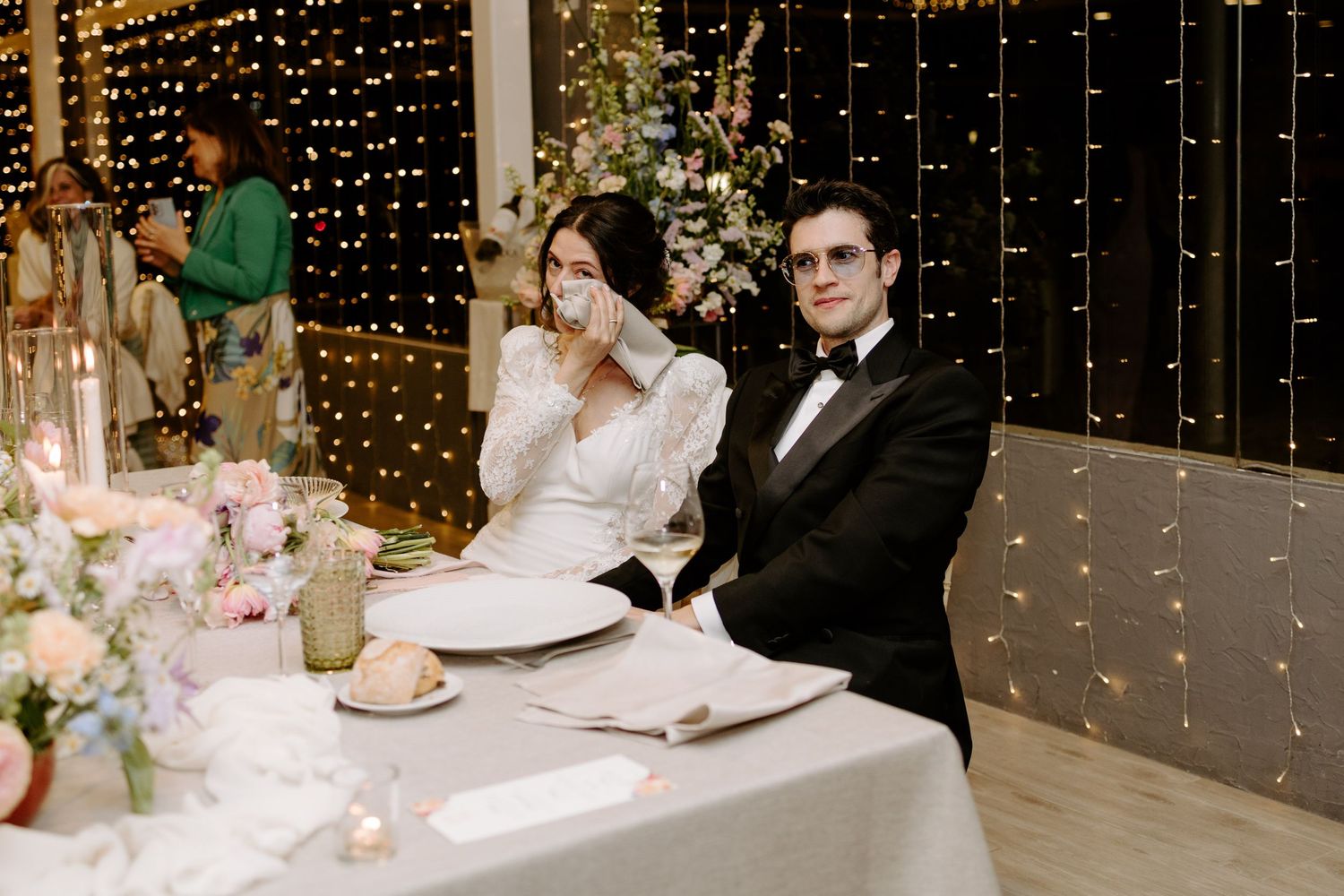 Reception guests seated at decorated tables with twinkling fairy lights creating an intimate atmosphere.